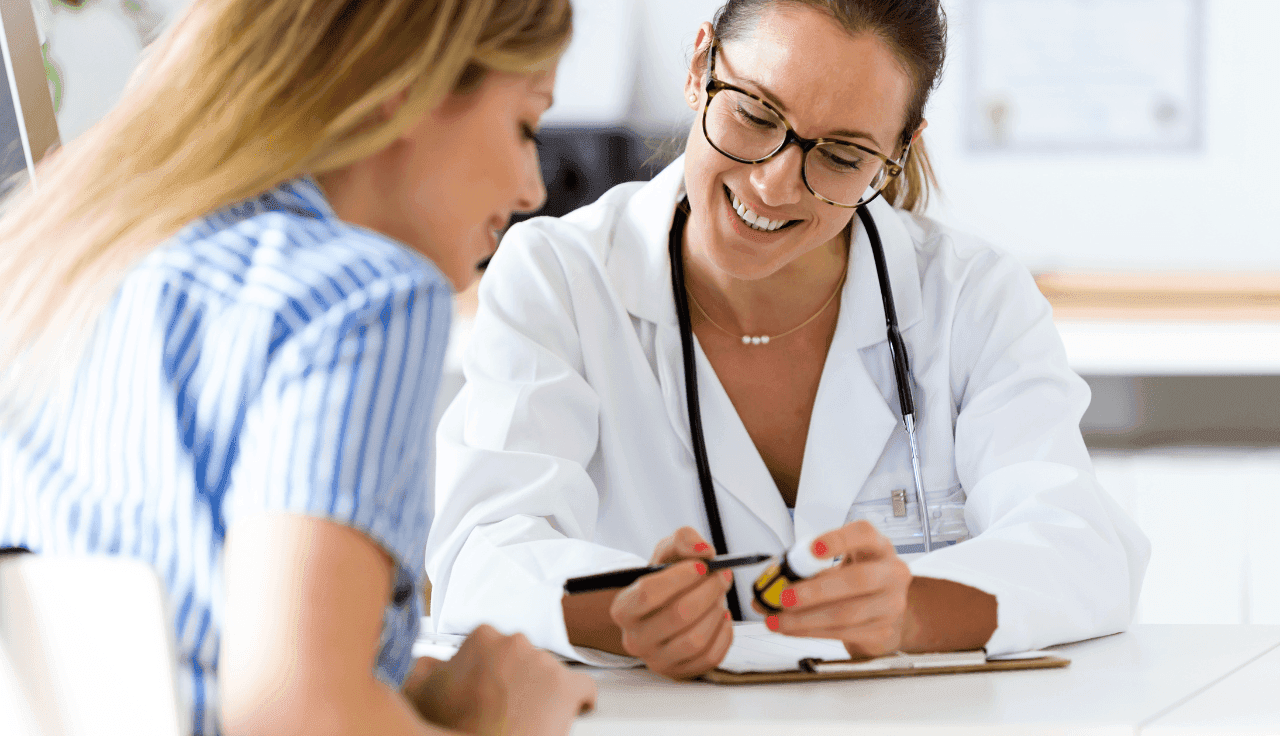 Ärztin zeigt Patientin eine Medikamentendose